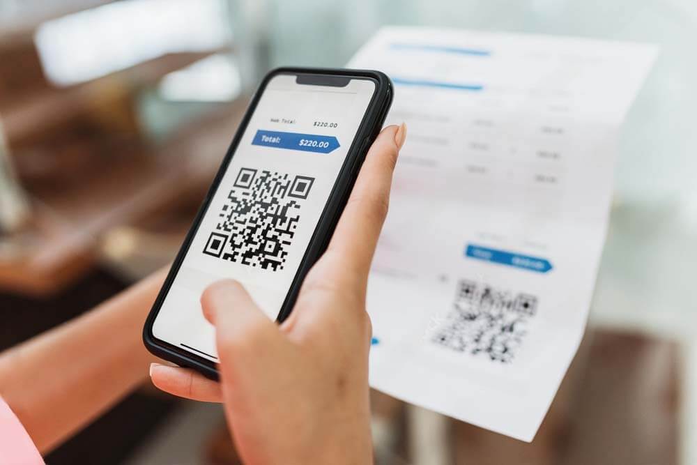 a woman booking scanning a qr code from an invoice